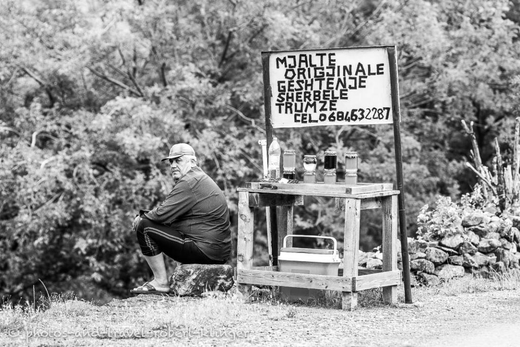 A man selling honey along the road in Albania, black and white photo
