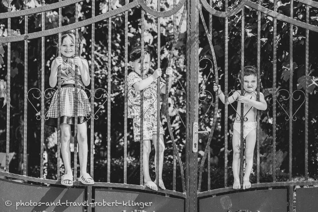 3 Children beyond an iron gate in Albania, black and white photo
