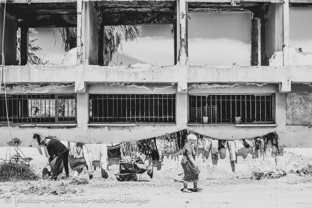 A man working and a woman drying laundry in front of a ruin in Albania, black and white photo