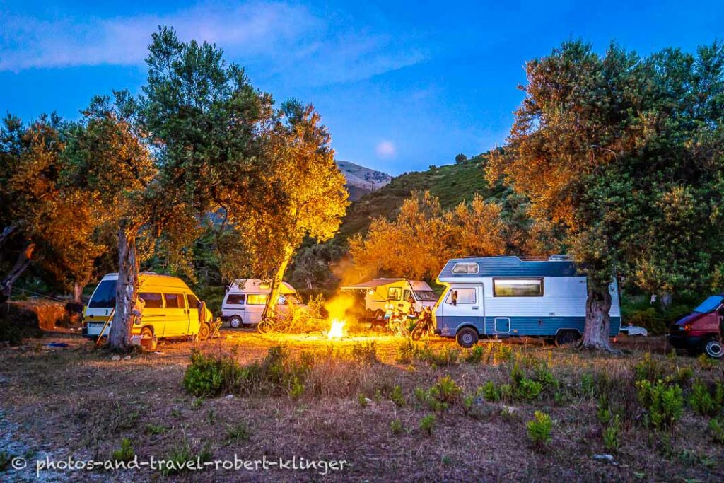 A campfire in the center of parked camping cars at a beautiful camping spot in Albania