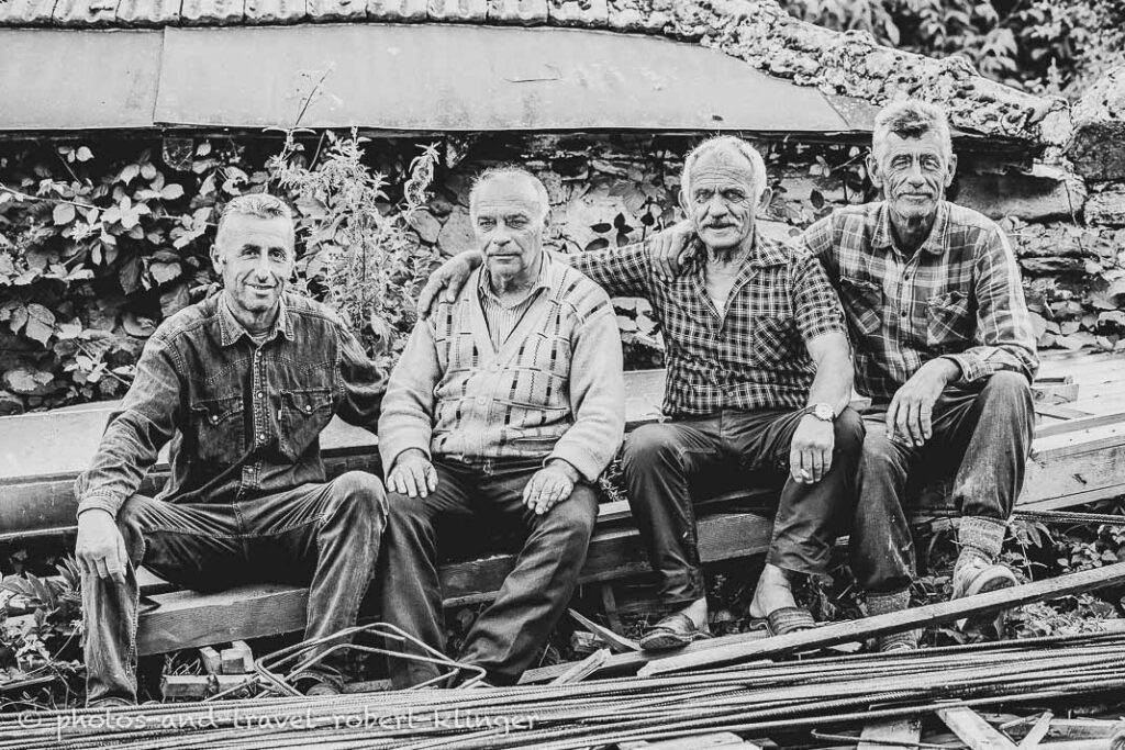 Four men sitting on a beam in a village in Northern Macedonia