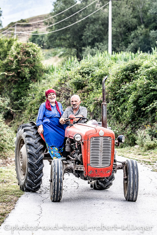 A travel photography portrait of a old happy farming couple on a tractor