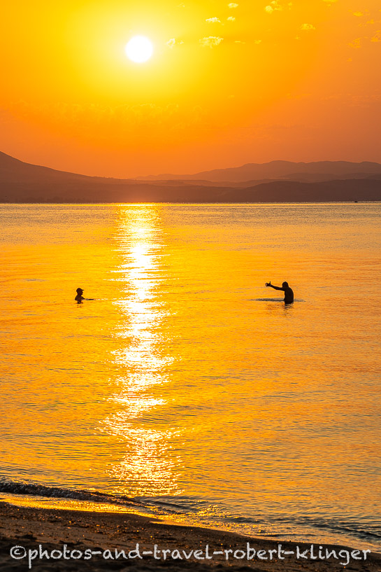 Two greek men talking in the sea during sunrise