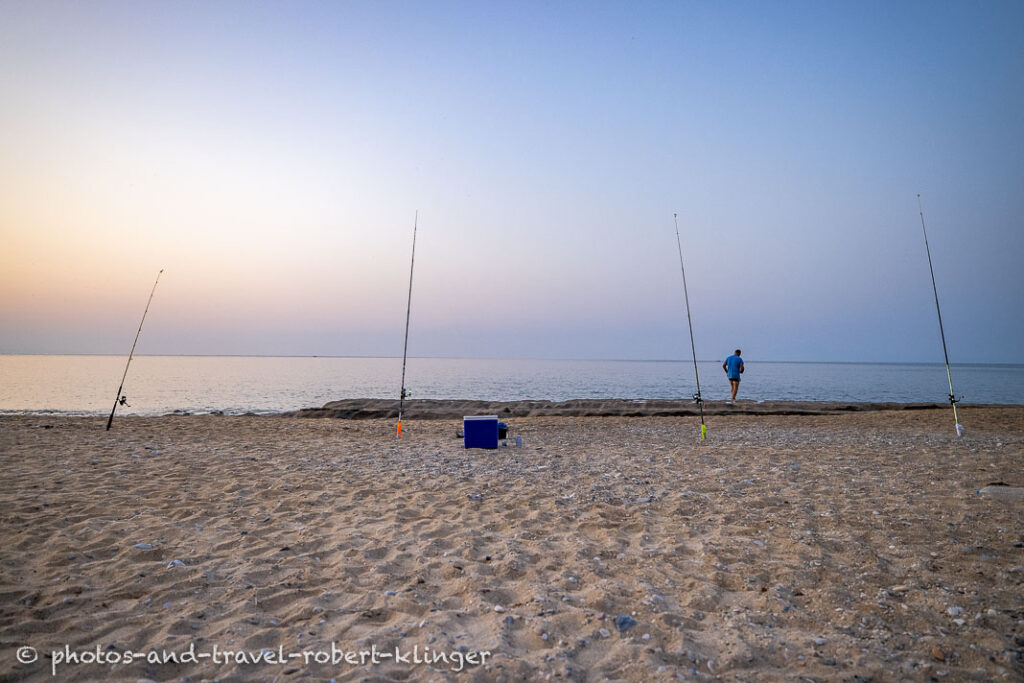 A fisherman fishing with 4 rods from the beach in Greece during sunsrise