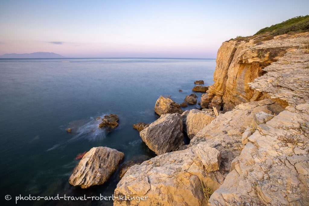 Long exposure photo of a sunrise on a stony and steep shore in Greece