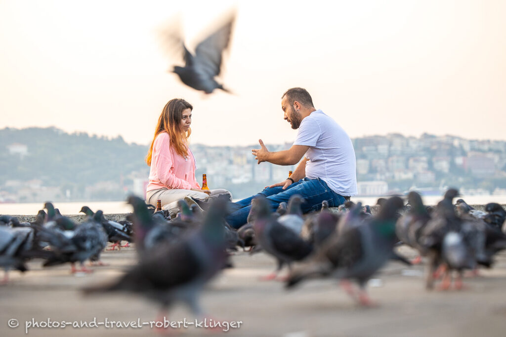 A young man and a woman having a conversation on an early morning at the shore of the Bosphorus in Istanbul