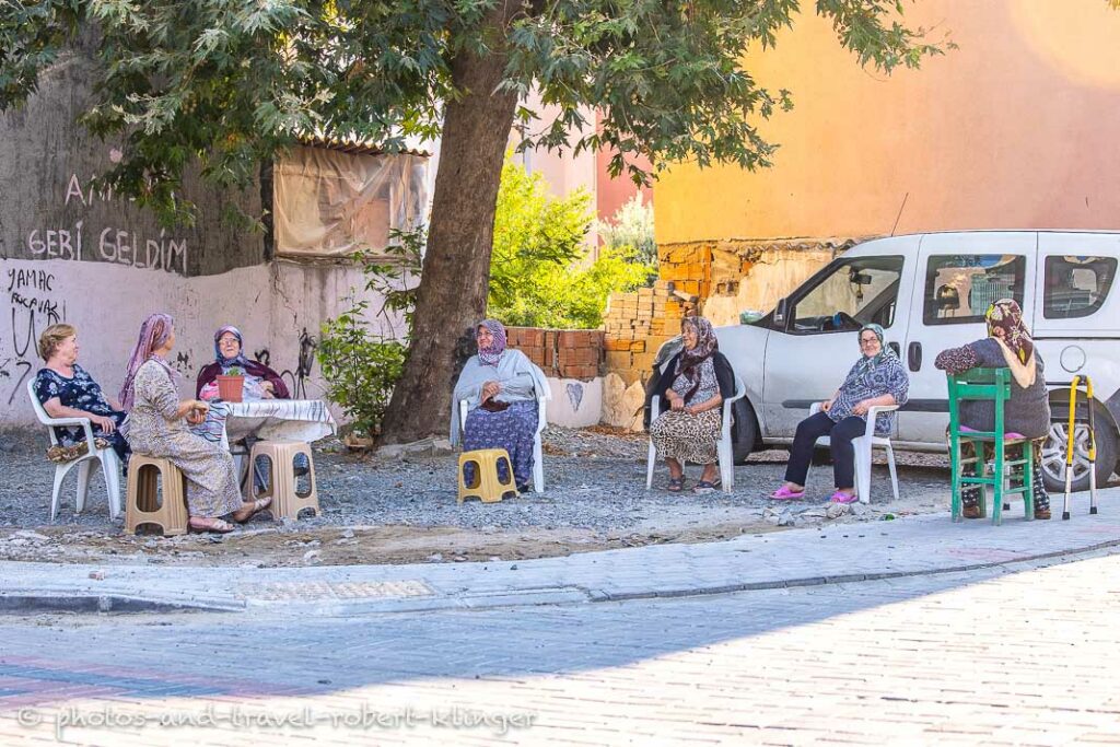 Turkish women are sitting together underneath a tree in a town in Turkey