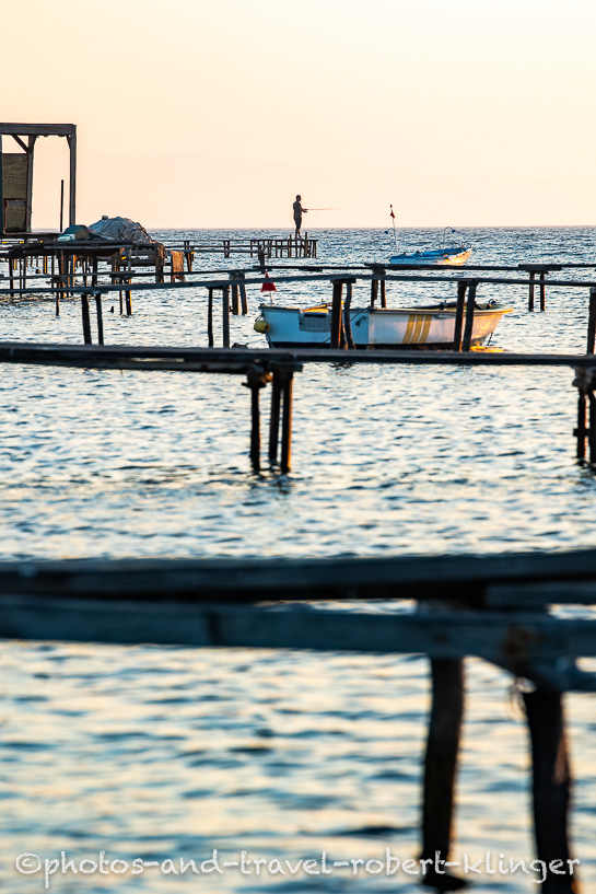 A man is fishing on an early morning from a jetty at the turkish west coast