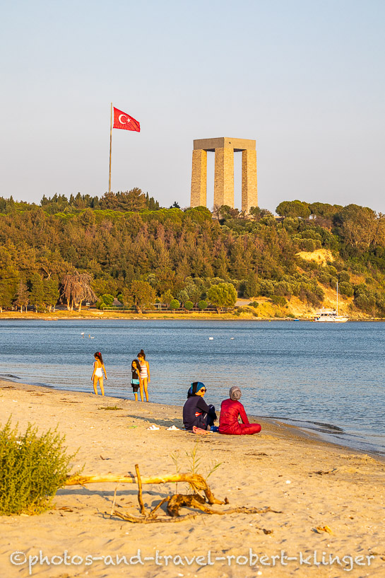 Two Women sitting on the beach in front of the Çanakkale Martyrs' Memorial on the Gallipoli Peninsula