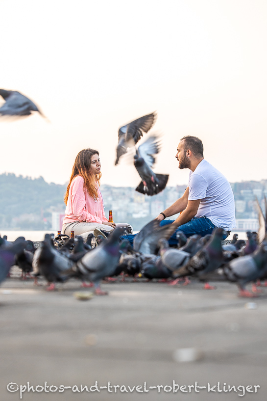 A young man and a woman having a conversation on an early morning at the shore of the Bosphorus in Istanbul