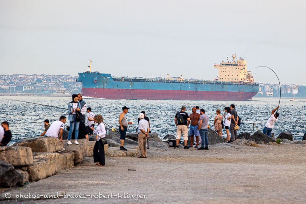 A big container ship in the Bosphorus in Istanbul and many people at the shoreline