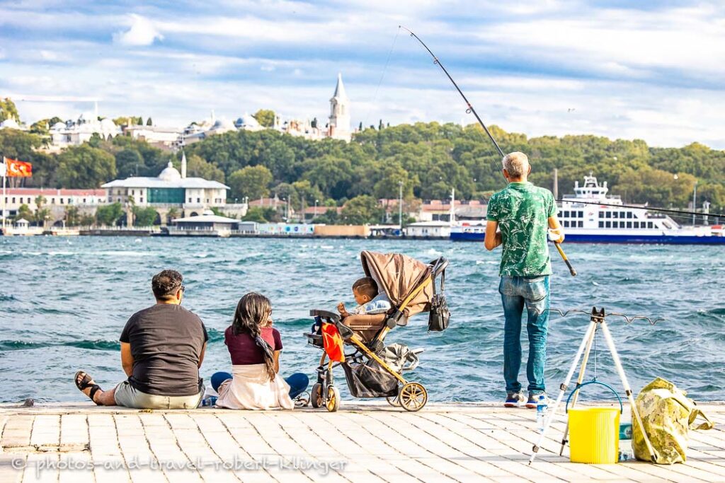 A man fishing and a family with their kid at the shore of the Golden Horn in Istanbul