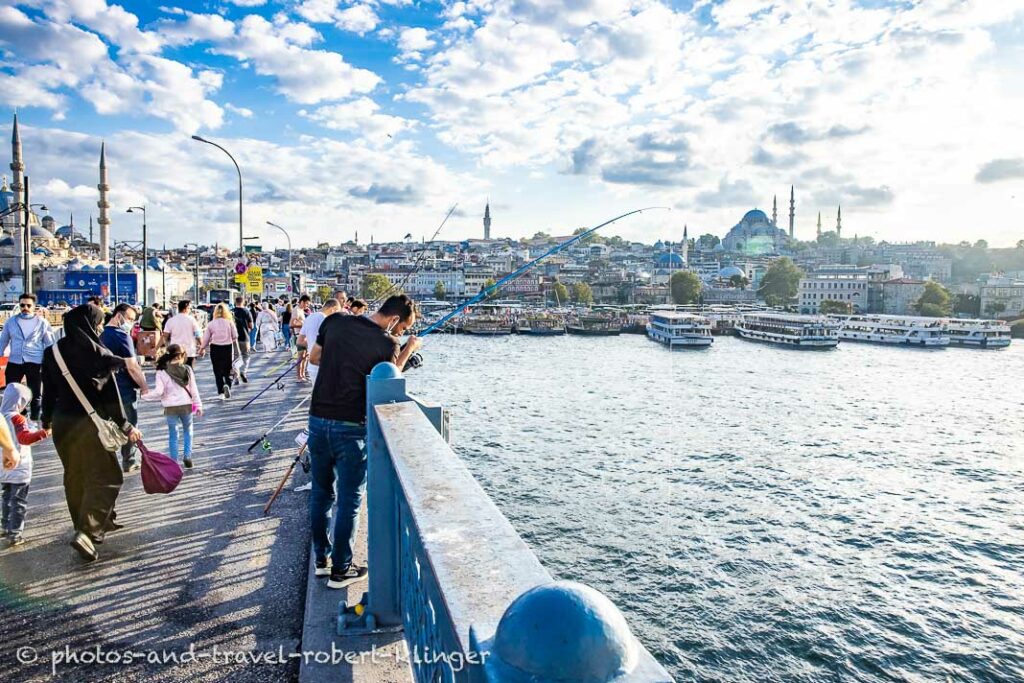 People fishing from and crossing Atatürk bridge in Istanbul