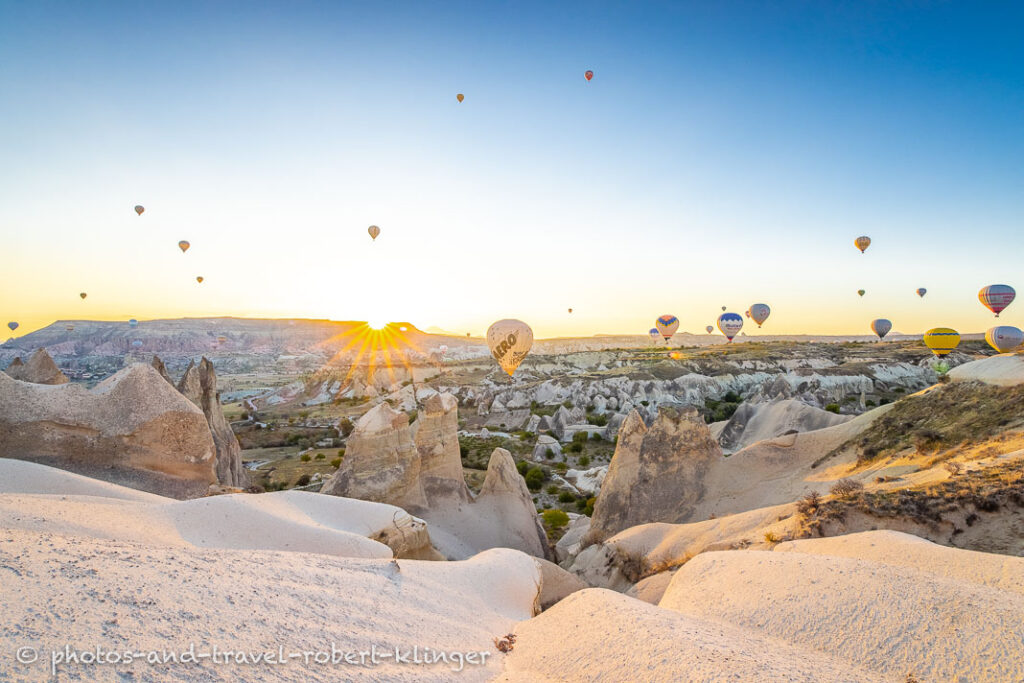 Sunrise over the Rose Valley in Cappadocia with many hot air ballons in the air