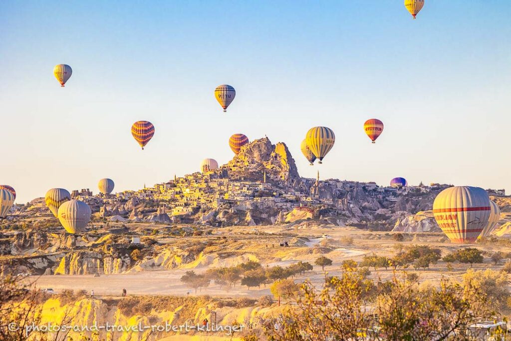 The town of Uchisar in Cappadocia and many ballons on an early morning