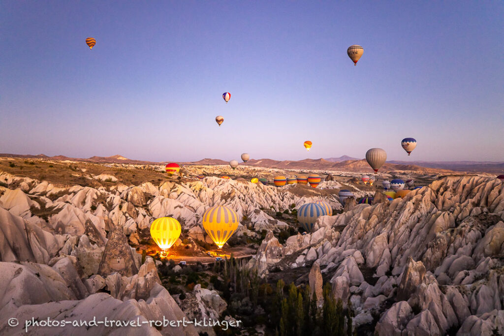 The first hot air ballons rising into the sky in Cappadocia during dawn