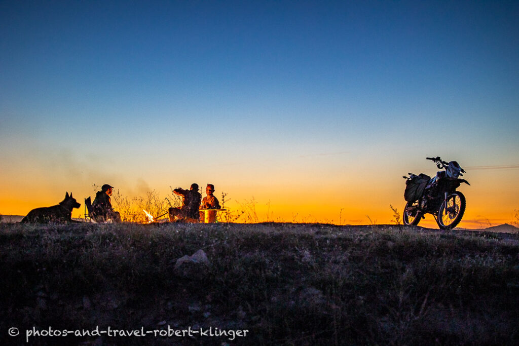 Three men and a dog sitting at a campfire during sunset in Cappadocia, Turkey