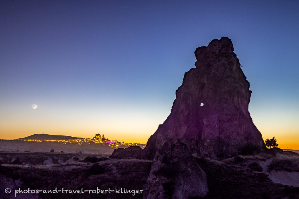 A big rock and the city of Uchisar in Cappadocia during sunset