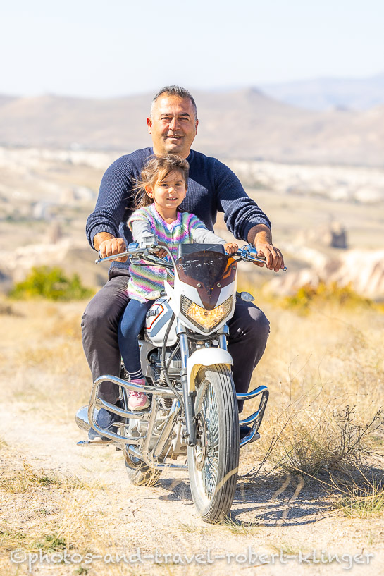 A turkish man and his doughter riding on a motor bike in Cappadocia