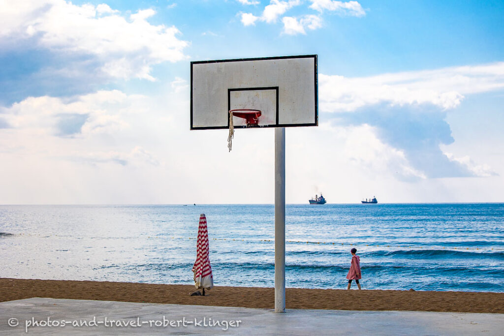 A basketball field very close to the beach of Inkum and a woman walking by the sea