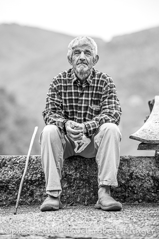 A old man sitting on a wall in a village at the Black Sea Coast in Turkey
