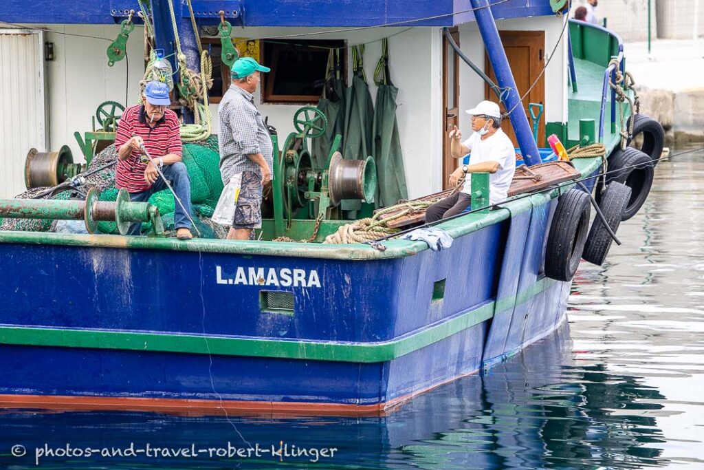 Three old men fishing from a boat in the harbour of Amasra