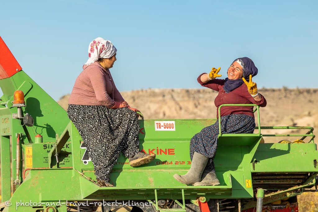 Two turkish women having a conversation on a tractor while harvesting pumpkin seeds