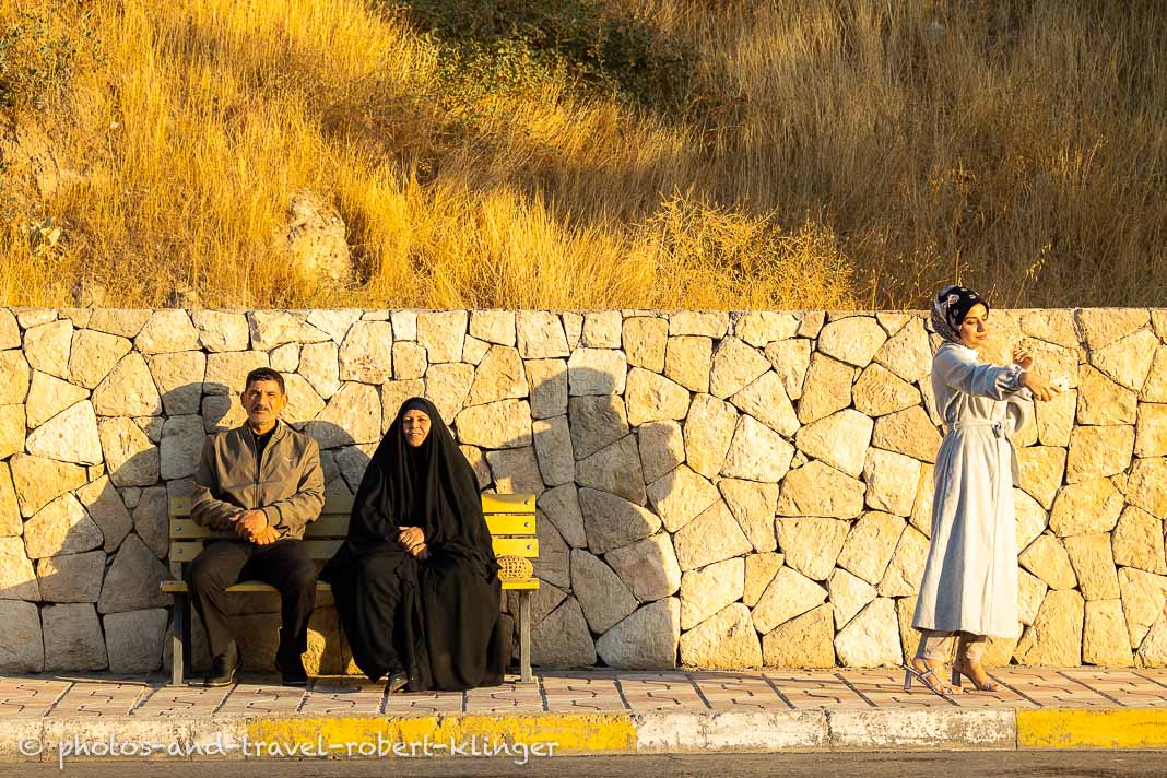 A iraq couple sitting on a bench and their doughter taking a selfie in Dohuk, Iraq