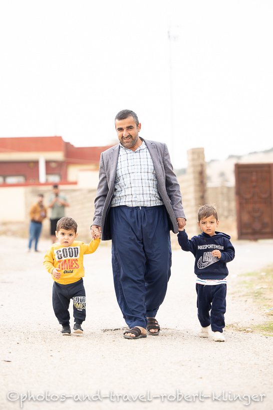 An iraqi man walking with his two sons through his village in Kurdistane