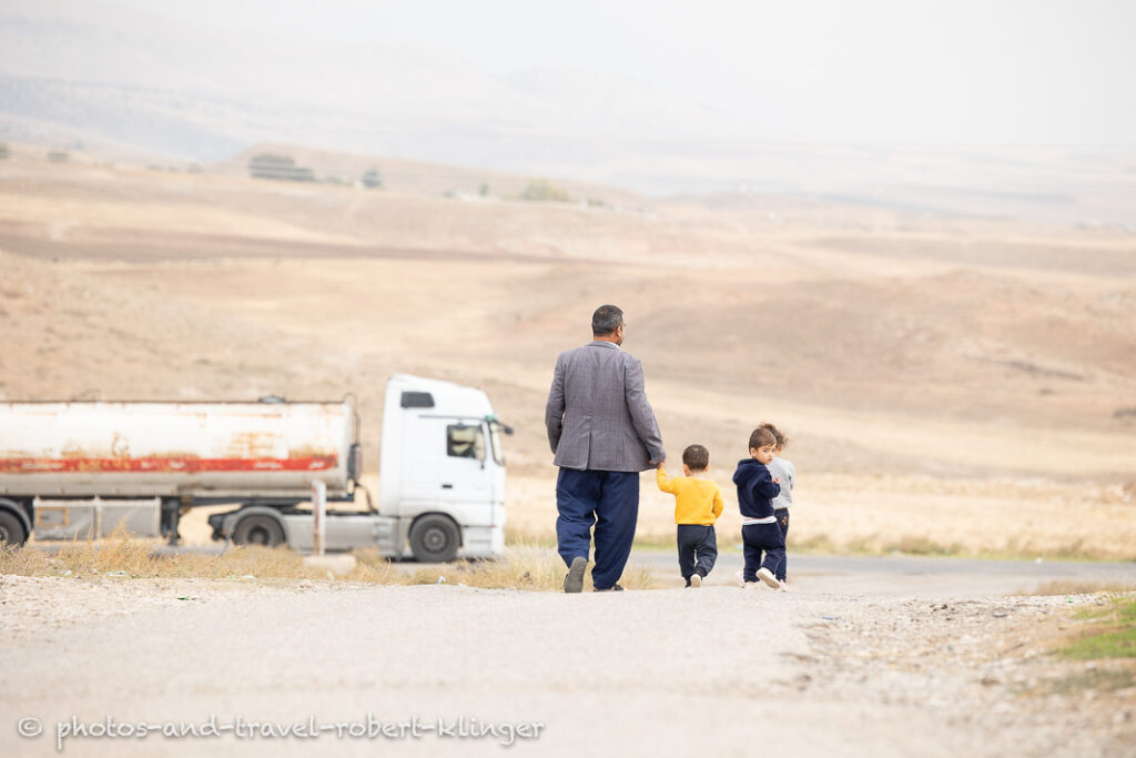 An iraqi man walking with his children around his village