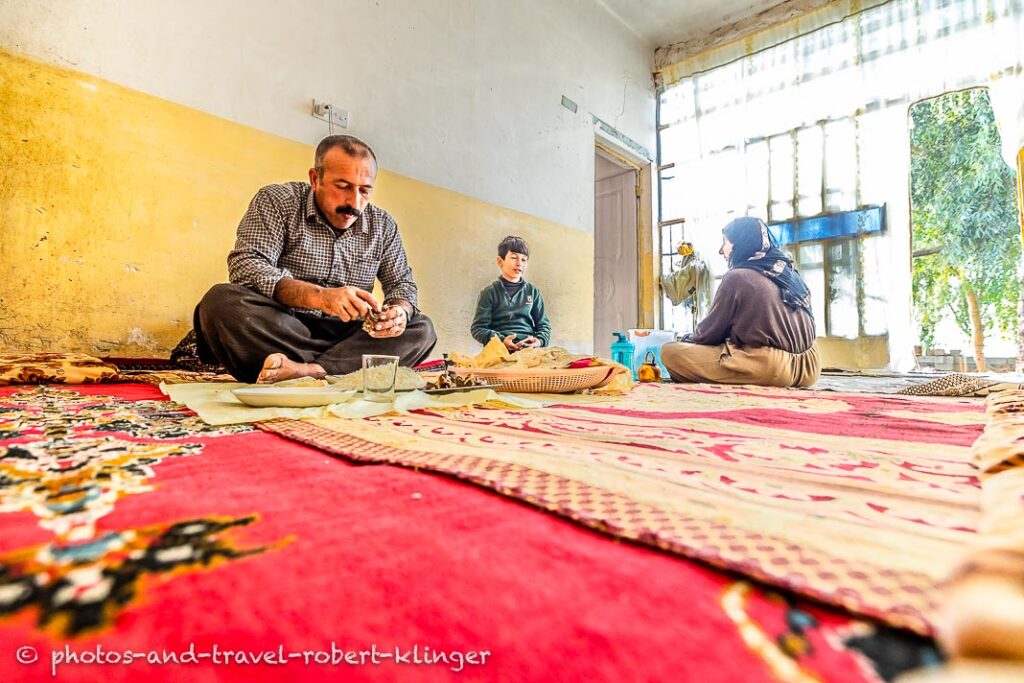 A kurdish family is having lunch in their living room in a village at lake Dukan, Kurdistan