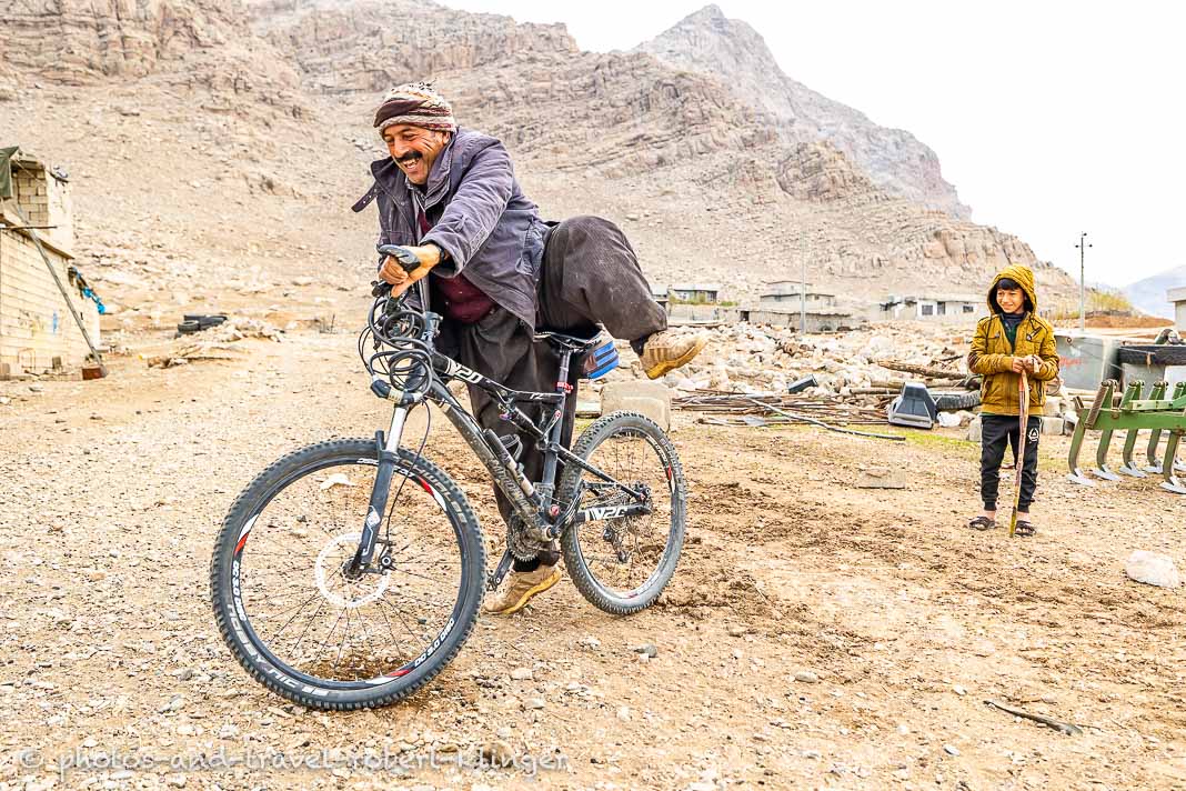 A kurdish farmer trying to ride a mountainbike and loughing