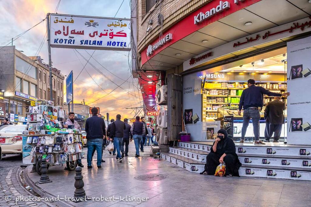 A woman is sitting in front of a electric store in Erbil, Kurdistan