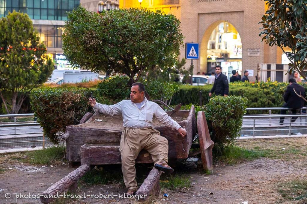 A kurdish man is taking a selfie in a park in Erbil