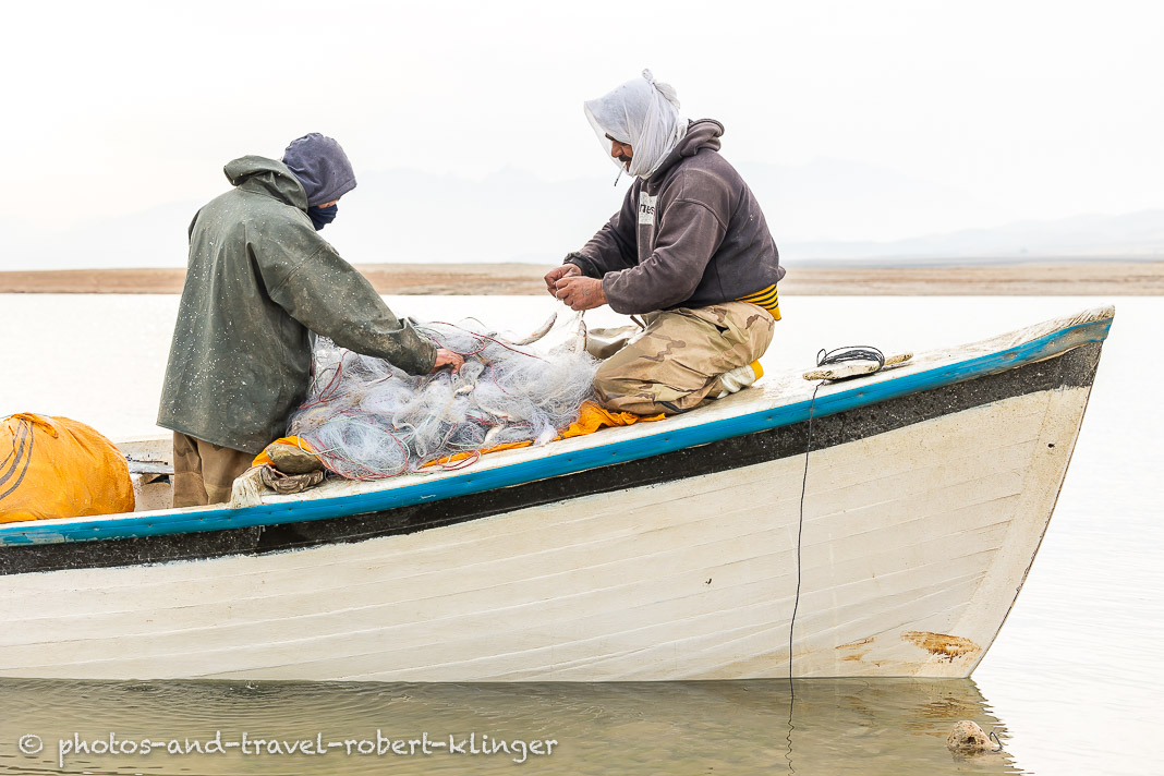 Two fishermen taking fish outh of their fishing nets at Lake Dukan