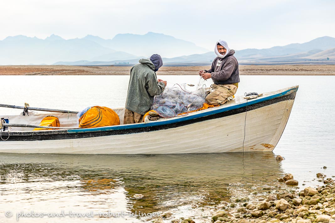 Two fishermen taking fish outh of their fishing nets at Lake Dukan