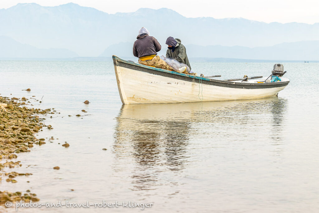 Two fishermen taking fish outh of their fishing nets at Lake Dukan