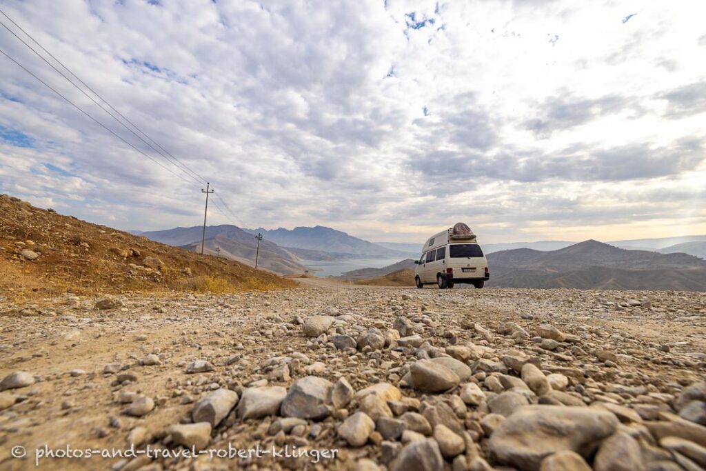 A Volkswagen camping van on a gravel road in Kurdistane, Iraq, at Lake Dukan