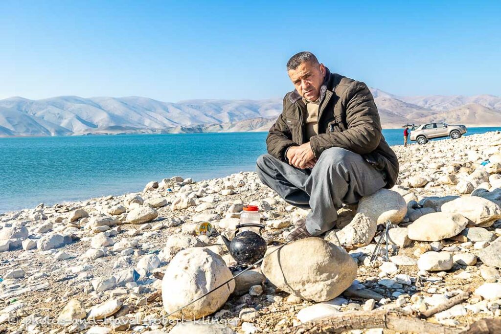 A kurdish fisherman sitting at a campfire and cooking tea at Lake Dukan