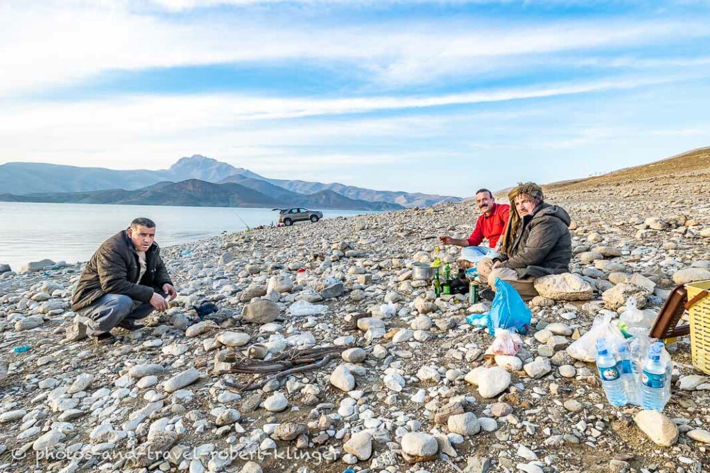 Three kurdish men sitting around a campfire at Lake Dukan