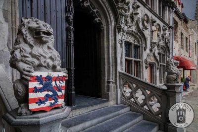 A lion statue with the city coat of arms of stands guard in front of the Basilica of the Holy Blood in Bruges Belgium. Photo by Photo Tour Brugge.