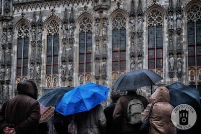A crowd of visitors inspect the facade of the city hall (Stad) in Bruges Belgium as the rain sets the mood. Photo by Photo Tour Brugge.