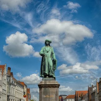 The statue of Flemish painter Jan Van Eyck standing at the former shipping port of Bruges Belgium. Photo by Photo Tour Brugge.
