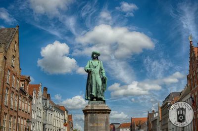 The statue of Flemish painter Jan Van Eyck standing at the former shipping port of Bruges Belgium. Photo by Photo Tour Brugge.