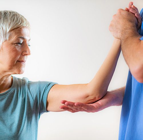 Therapieanwendung Physiotherapeut stützt Arm von Patient