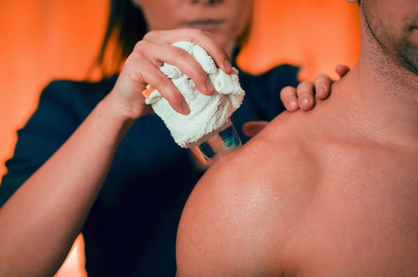 Kältetherapie Therapieanwendung Physiotherapeut legt Patient einen Kältewickel auf die Schulter