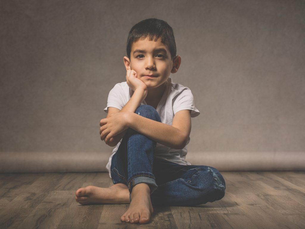 dreng på 6 år sidder på trægulv i jeans