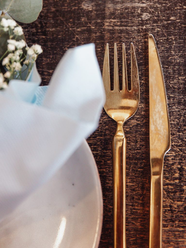 kniv og gaffel i guld ved smuk opdækning til barnedåb