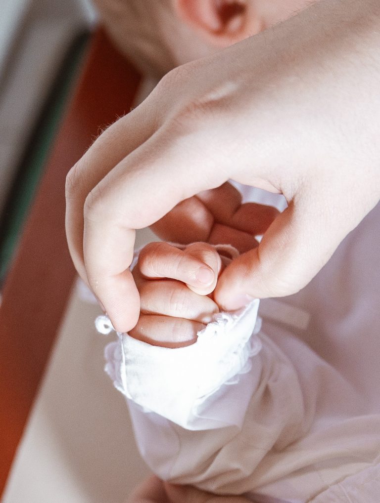 mor giver baby dåbskjole på inden barnedåbs fotografering