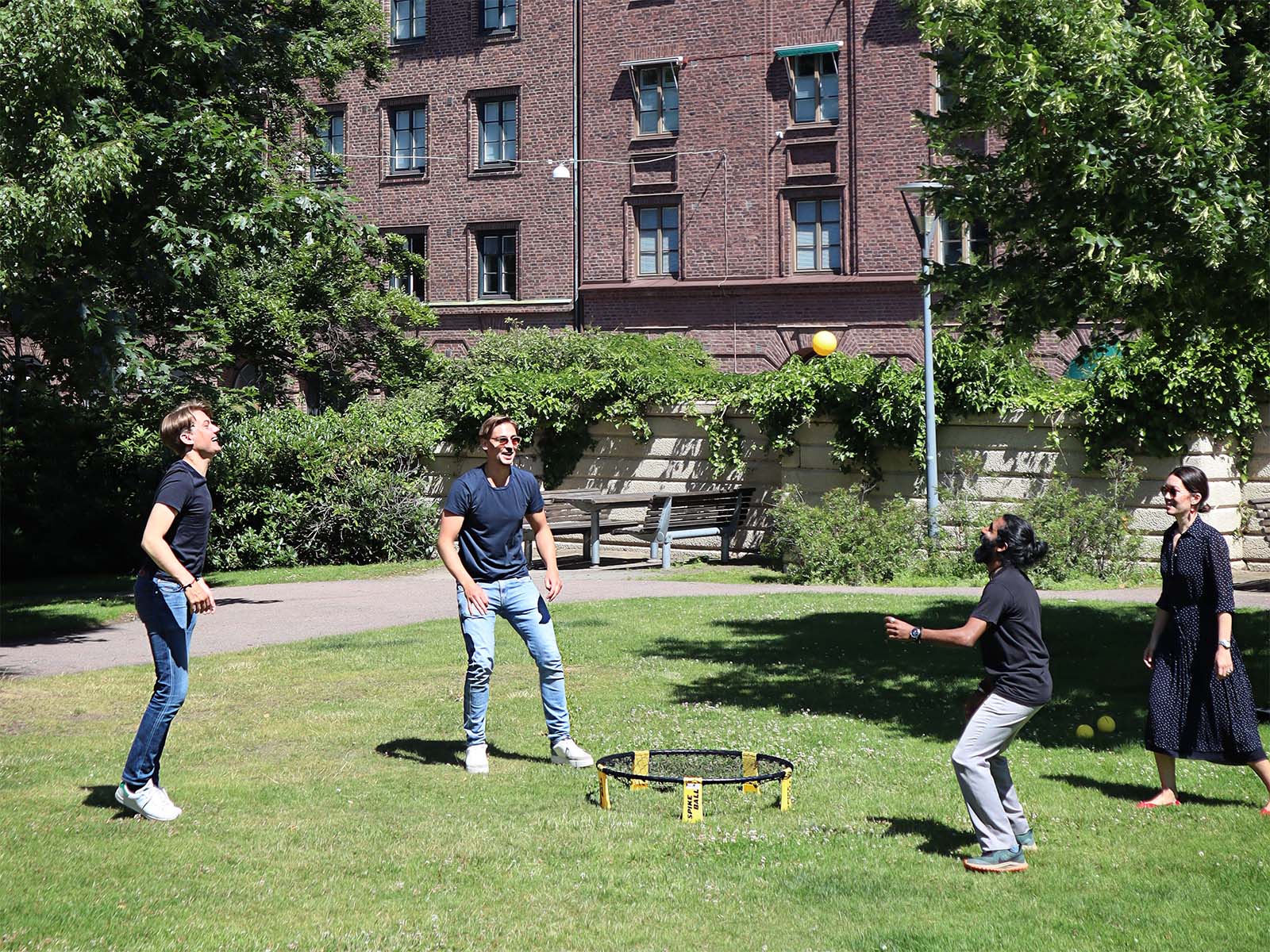 Fyra personer spelar spikeball i parken